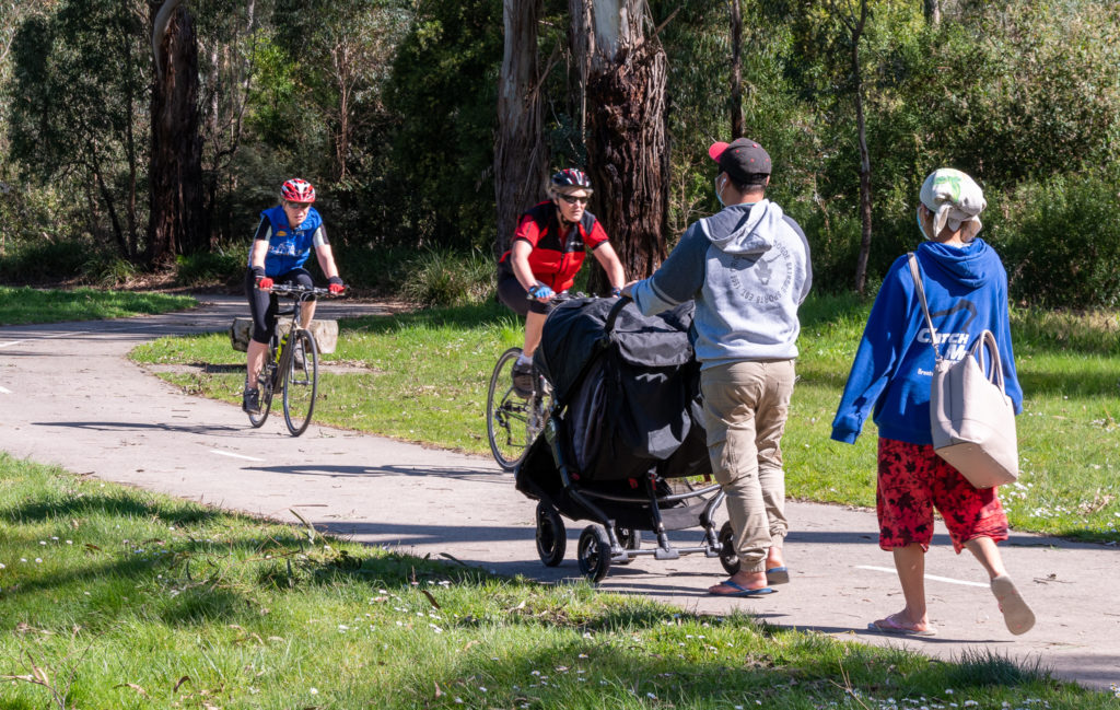 Parents pushing a twin pram along a shared Maroondah walking path with cyclists